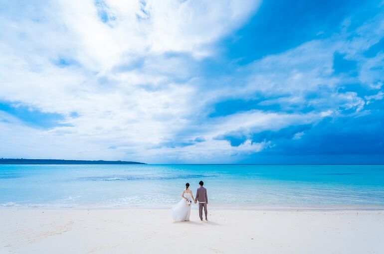 広い海と青い海を背景に手をつなぐ新郎新婦様