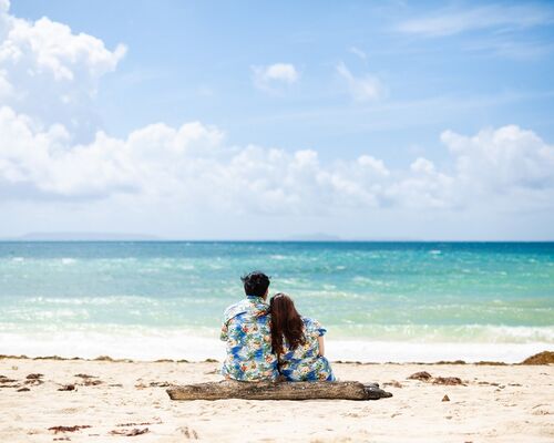 沖縄ウェディングフォトで海のそばで座るカップル